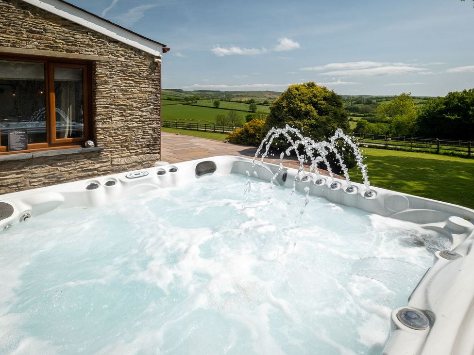 A hot tub with water jets and a stone wall at Blaenachddu in Newcastle Emlyn