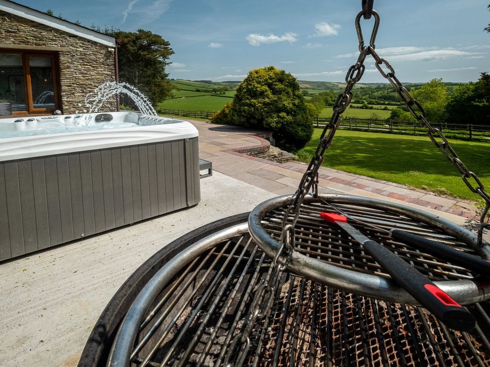A hot tub and grill on an outdoor patio at Blaenachddu Newcastle Emlyn