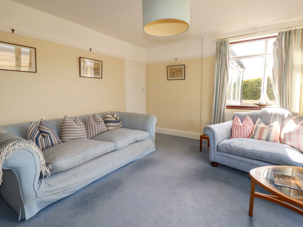 A living room with a blue sofa and a glass table at Chy-an-Lowena in Crantock