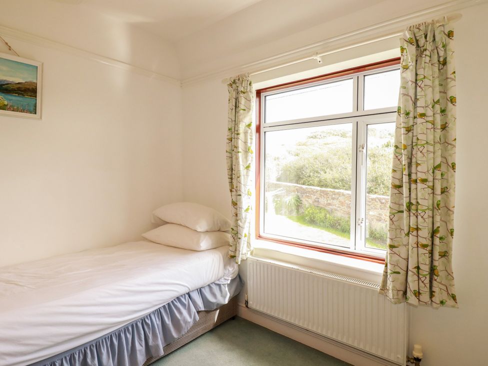 A bedroom with a bed and a window at Chy-an-Lowena in Crantock