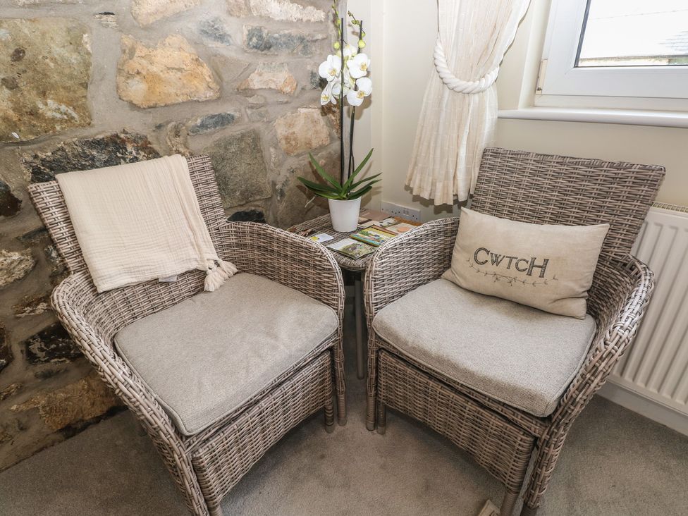 Two chairs with an orchid and a side table at Hafan y Tyddyn