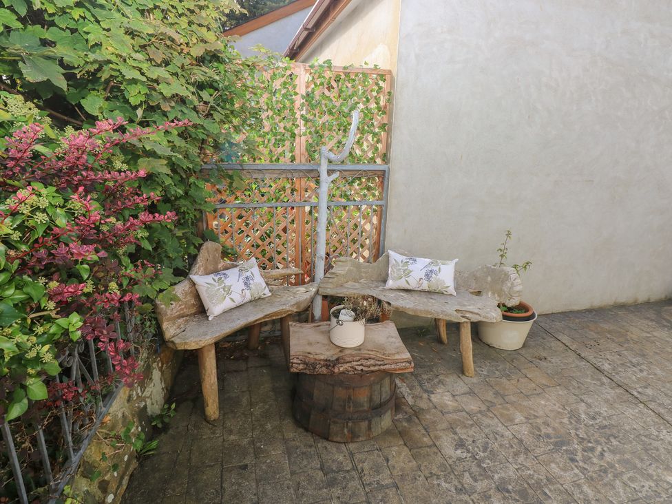An outdoor seating area with wooden benches and a table at Hafan y Tyddyn