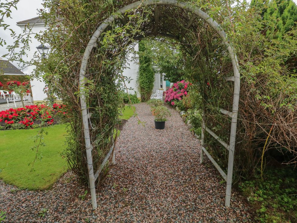 A garden with an archway and gravel path at Bruckless Rest Fine Country Dining B&B, Bruckless