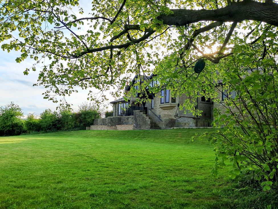 A garden with a house and trees at Castleys Mount in Skipton