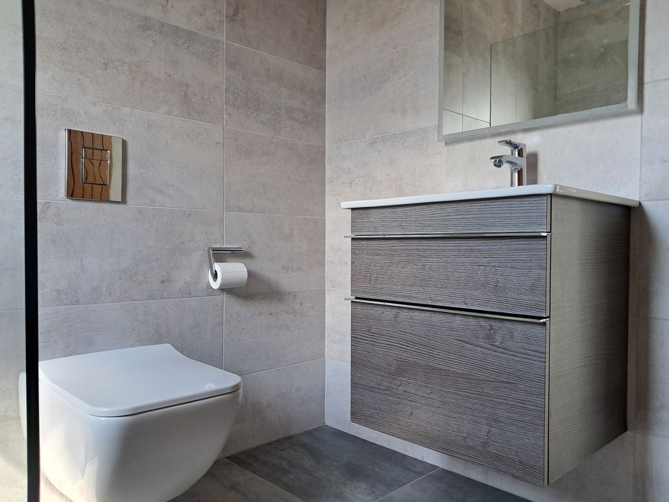 A bathroom with a toilet, sink, and mirror at Castleys Mount Skipton