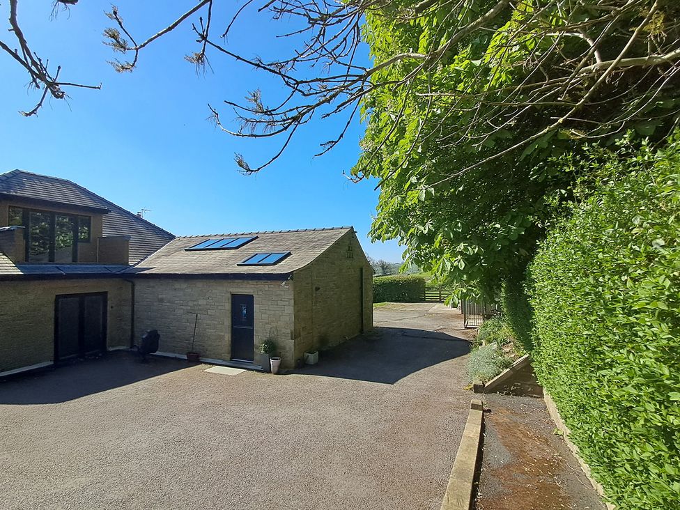 An outdoor area with a house, trees, and a driveway at Castleys Mount in Skipton