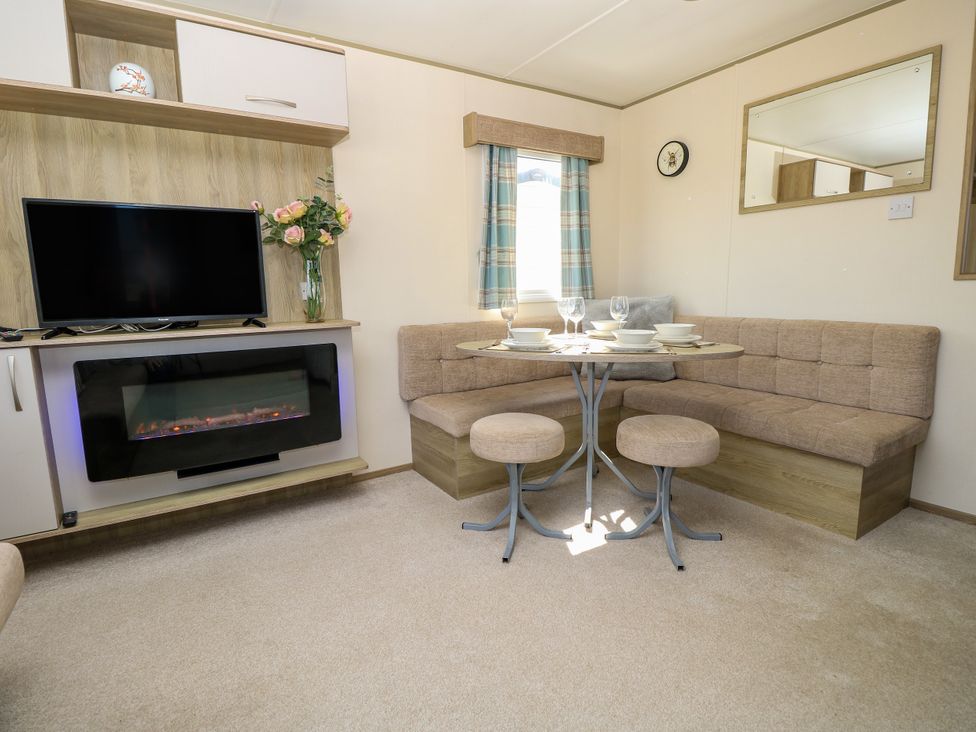 A living room with a dining area and television at Beach Retreat
