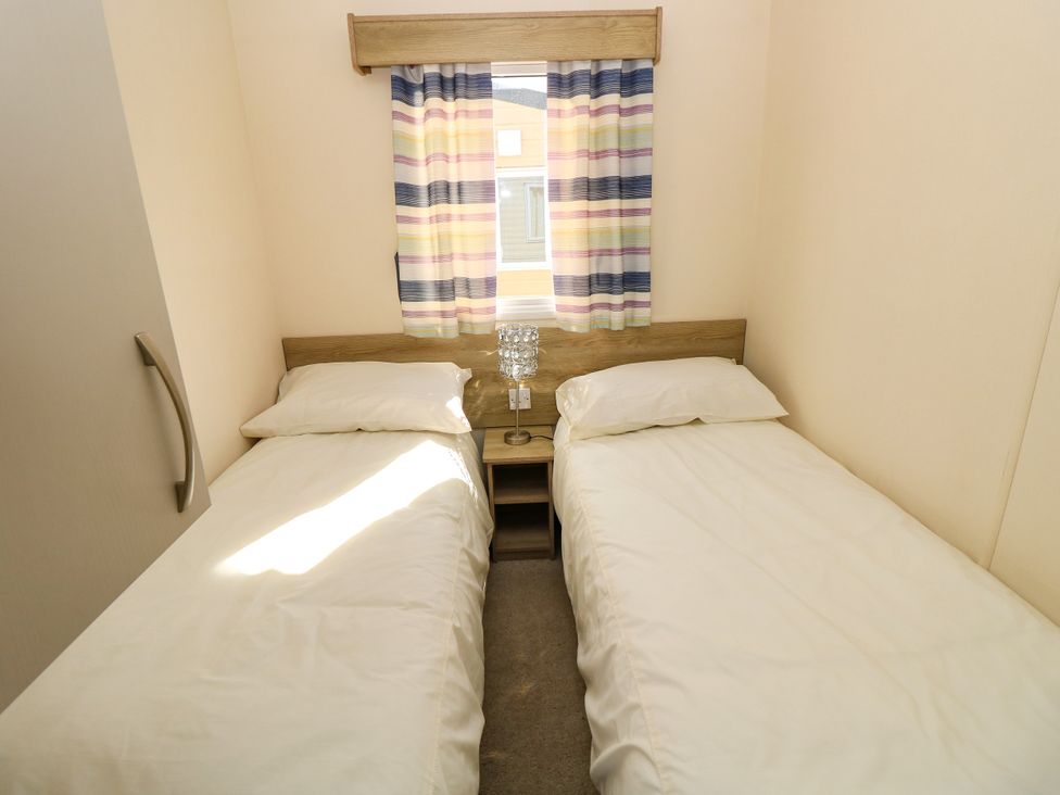 A bedroom with two single beds and a window at Beach Retreat