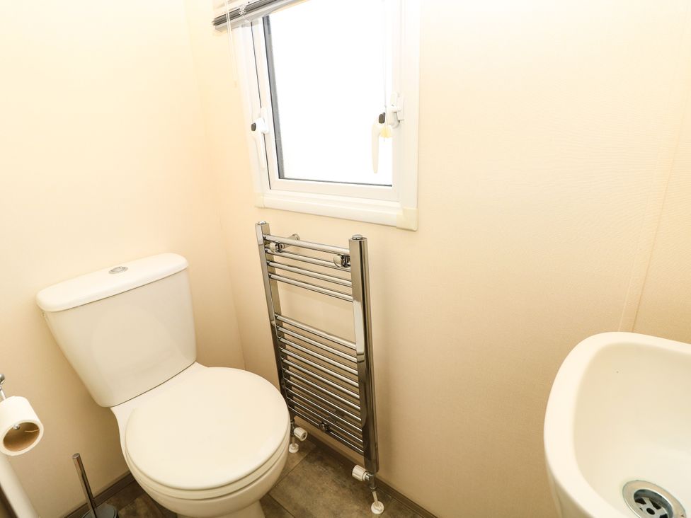A bathroom with a toilet, sink, and radiator at Beach Retreat