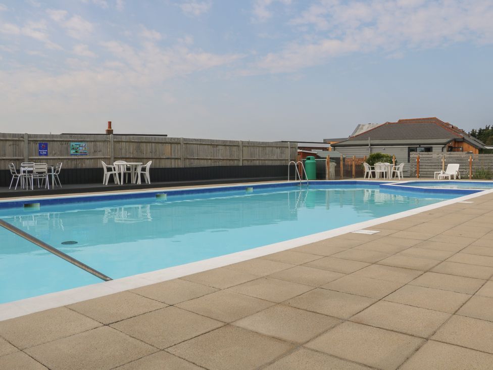 An outdoor swimming pool with tables and chairs at Beach Retreat in 