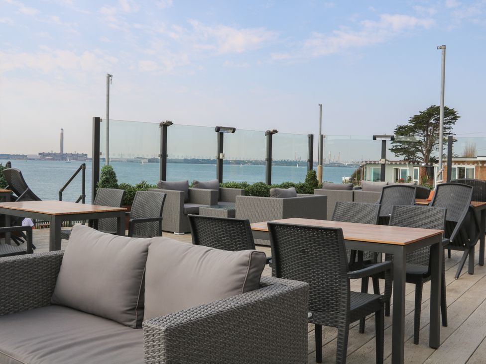 An outdoor terrace with seating and tables overlooking waterfront at Beach Retreat