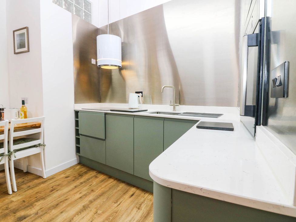 A kitchen with cabinets, sink, faucet, and dining table at The Studio @ 18 Milnathort