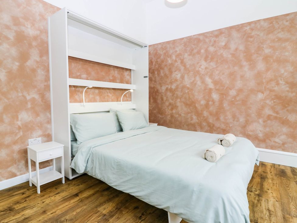 A bedroom with a folding bed frame and bedside table at The Studio @ 18 Milnathort