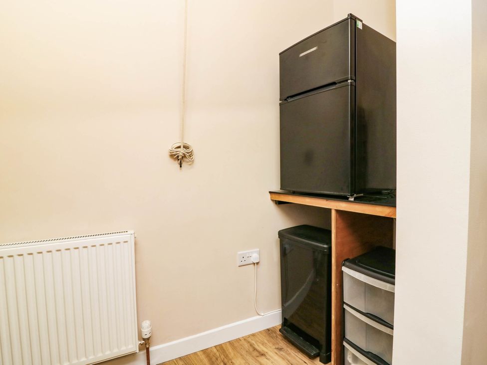 A utility room with a refrigerator and storage bins at The Studio @ 18 Milnathort
