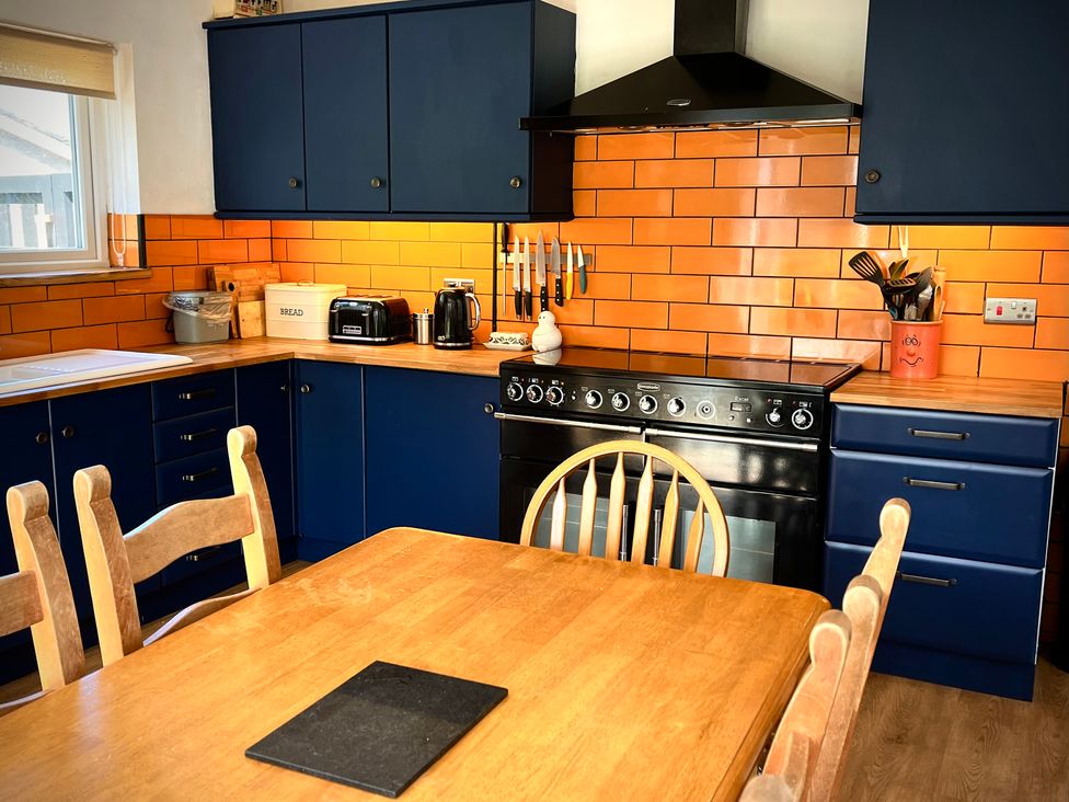 A kitchen with blue cabinets and wooden table at Ty Marlyn in St Davids