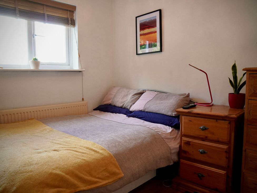 A bedroom with a bed, nightstand, and window at Ty Marlyn in St Davids