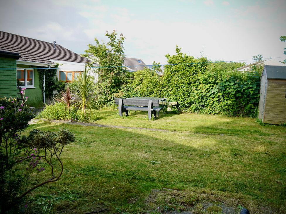 A garden with a table and benches at Ty Marlyn in St Davids