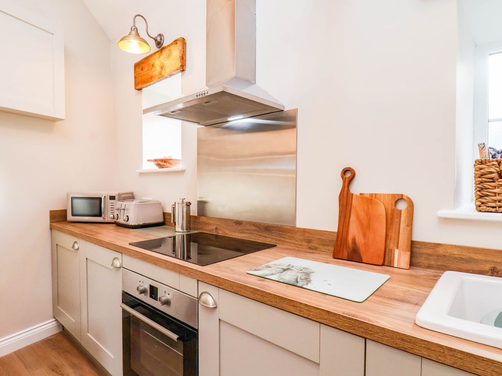 A kitchen with countertops, microwave, and cooking hob at Tawny Cottage in Scarborough