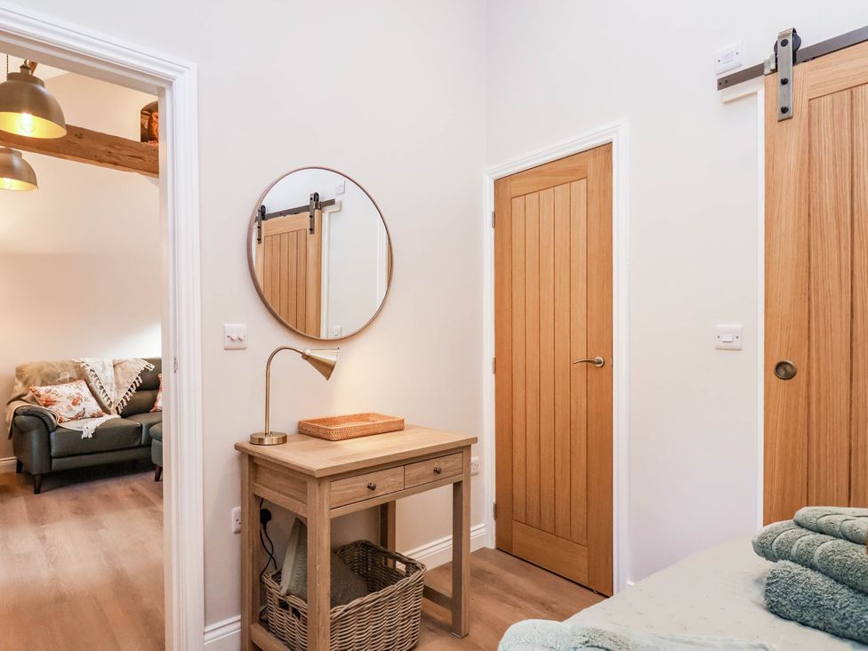 A bedroom with a table, mirror, and door at Tawny Cottage in Scarborough