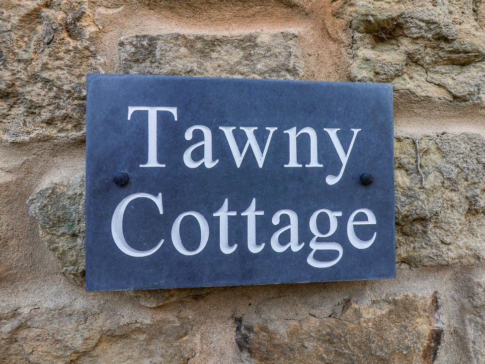 A sign reading Tawny Cottage on a stone wall at Tawny Cottage Scarborough