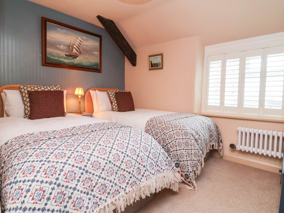 A bedroom with twin beds and a painting at Myrtle Cottage in Lynmouth