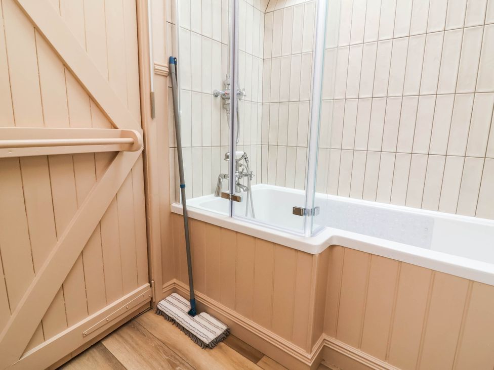 A bathroom with a bathtub and cleaning mop at Myrtle Cottage in Lynmouth