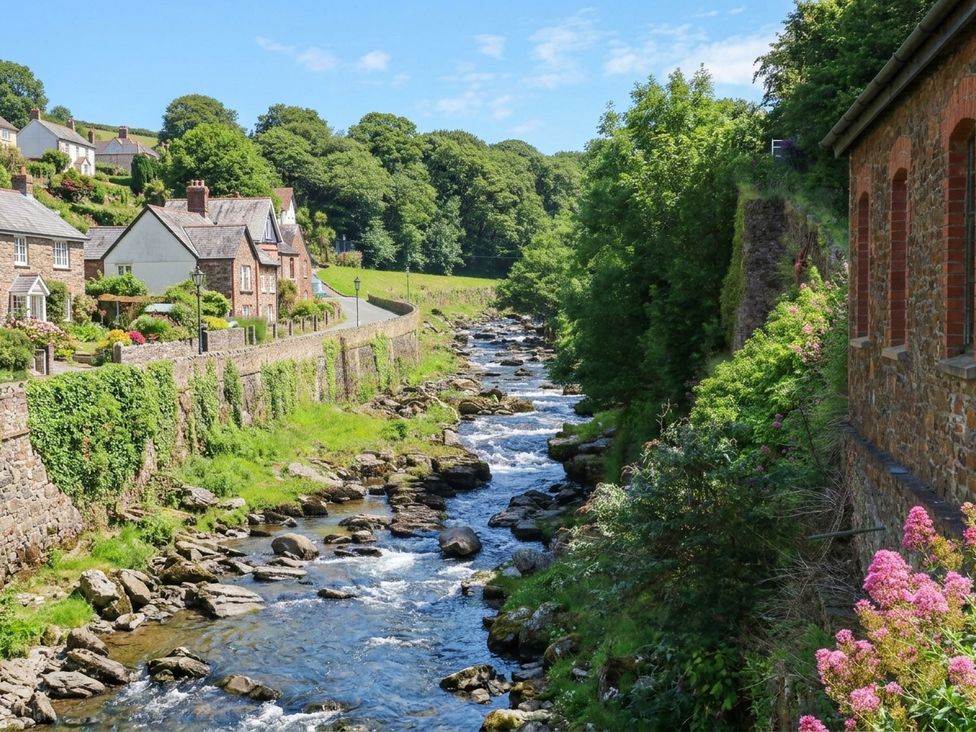 A stream with rocks and houses alongside it at Myrtle Cottage in Lynmouth