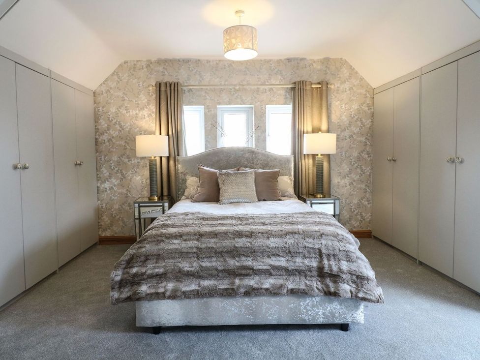 A bedroom with a bed, lamps and wardrobes at Old Print House Ilkeston
