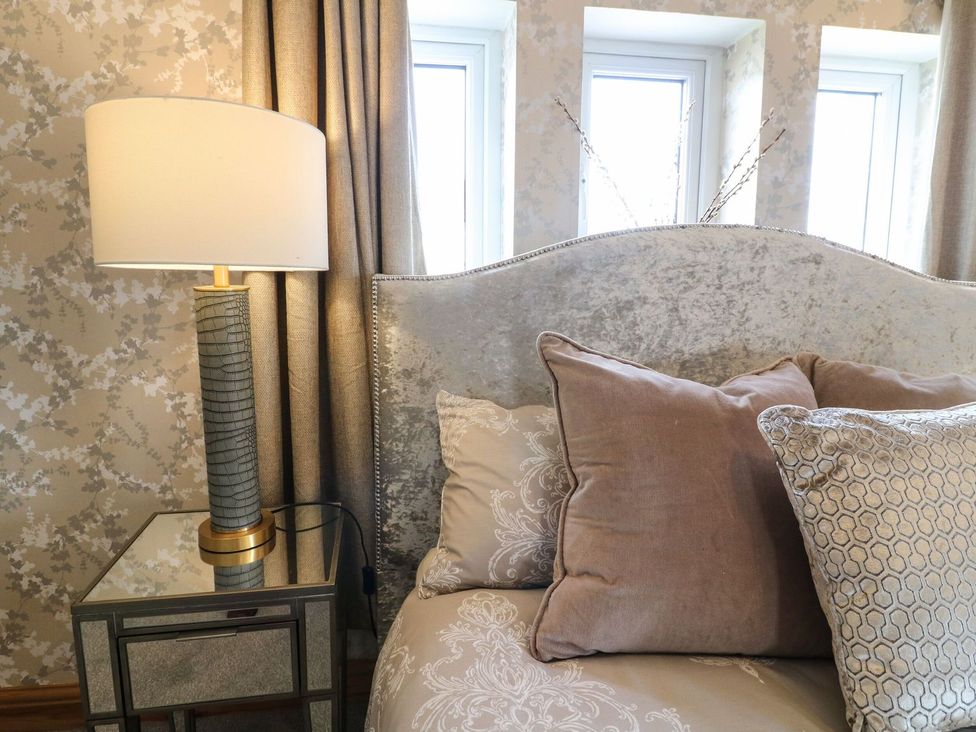 A bedroom with a lamp and pillows on a bed at Old Print House in Ilkeston