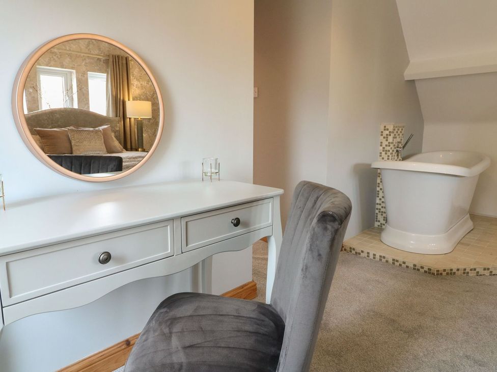 A bedroom with a vanity, mirror, and bathtub at Old Print House in Ilkeston