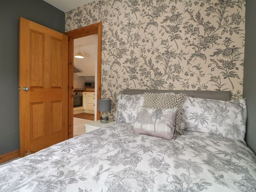A bedroom with a bed and open door leading to kitchen at The Old Print House Ilkeston
