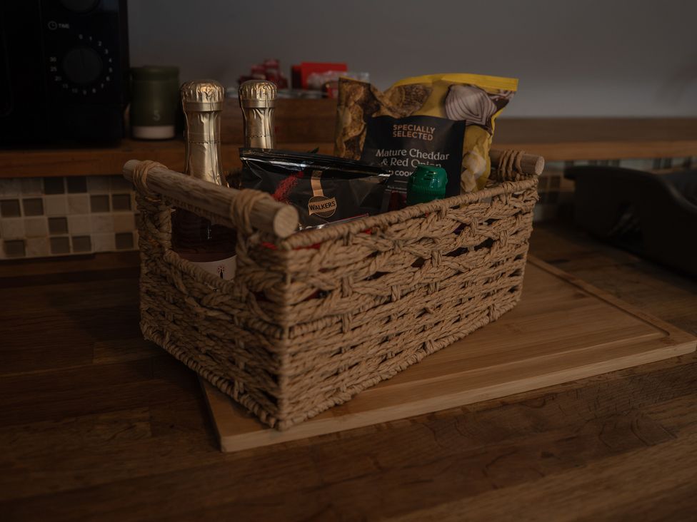 A basket with bottles and snacks on a wooden surface at The Old Print House in Stanley Common