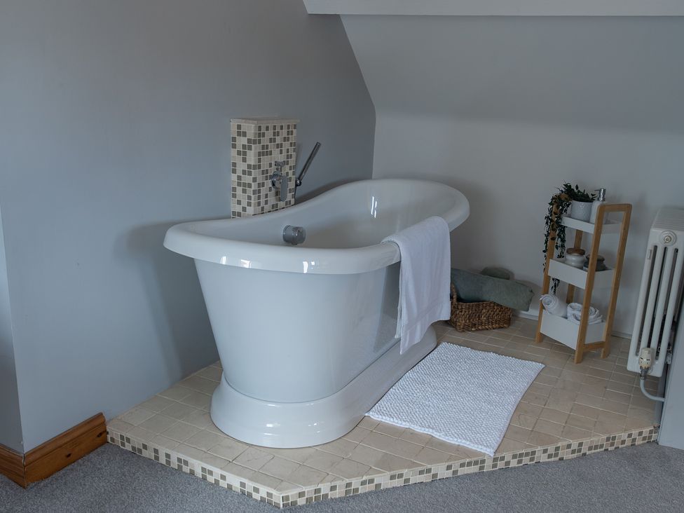 A bathroom with a bathtub and towels at The Old Print House in Stanley Common