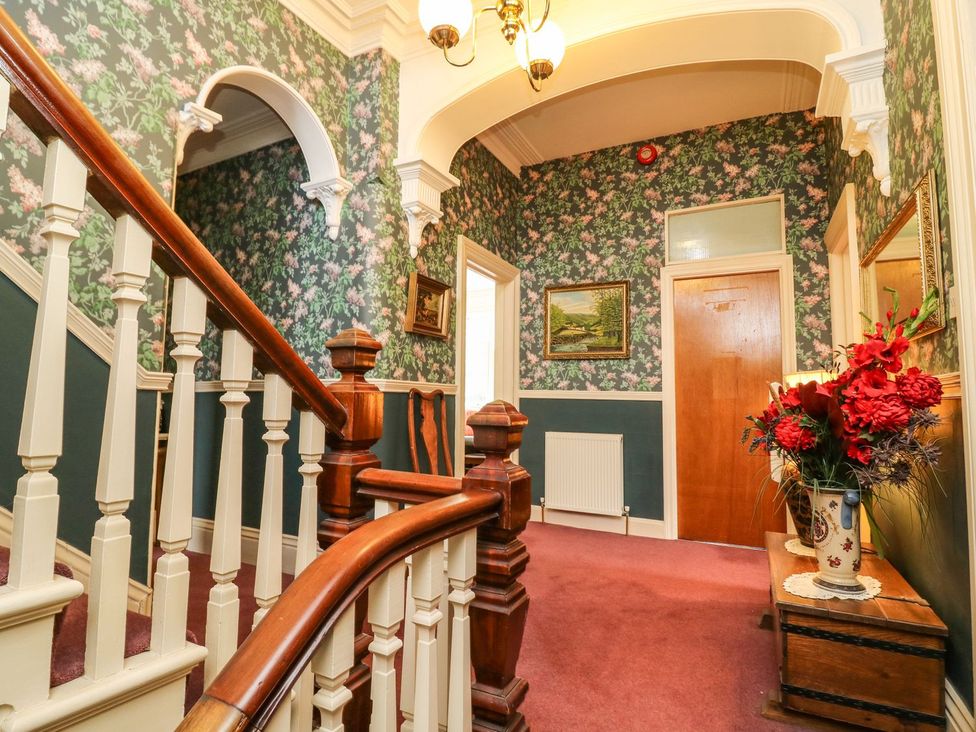 A hallway with a staircase and floral wallpaper at Ryburn Lodge in Bridlington