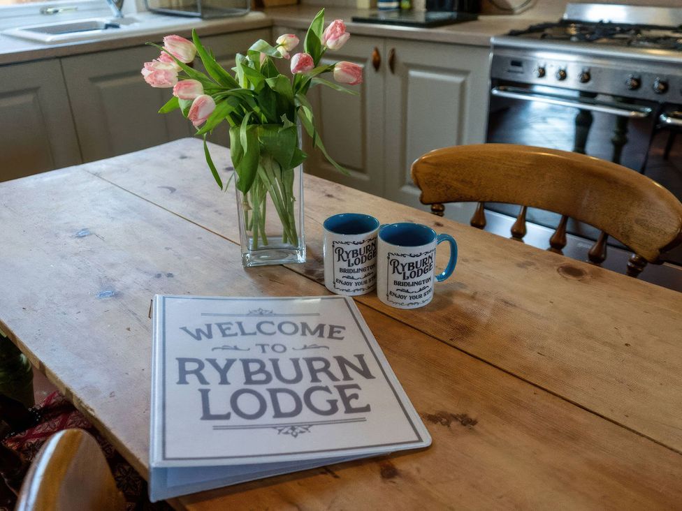 A kitchen table with flowers and welcome folder at Ryburn Lodge Bridlington