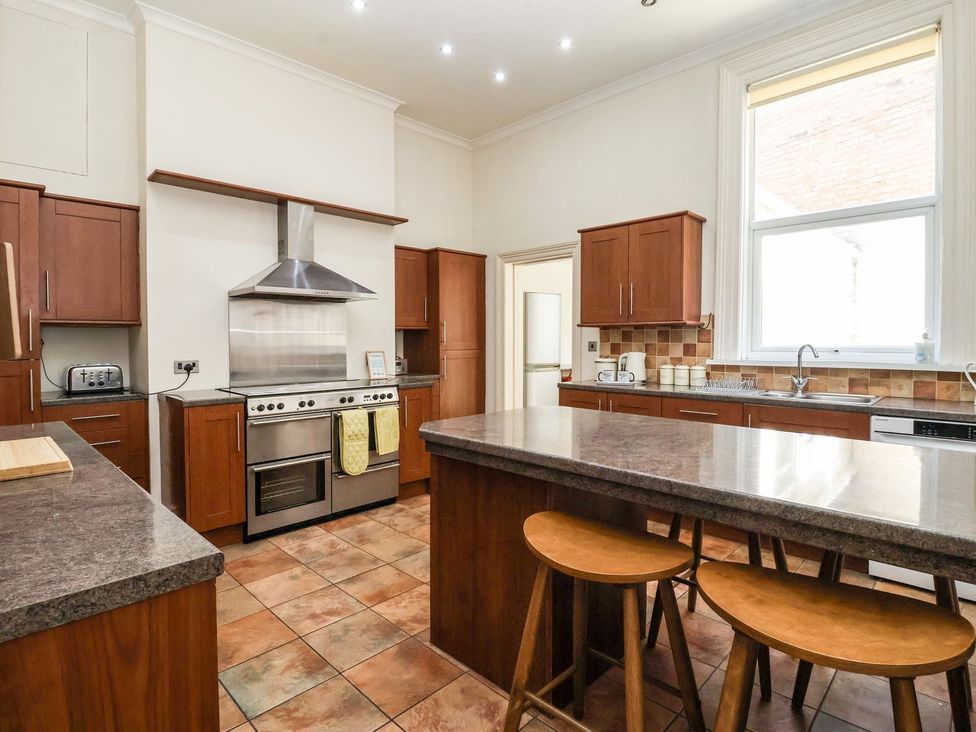 A kitchen with cabinets, stove, and bar stools at Trinity Lodge in Bridlington