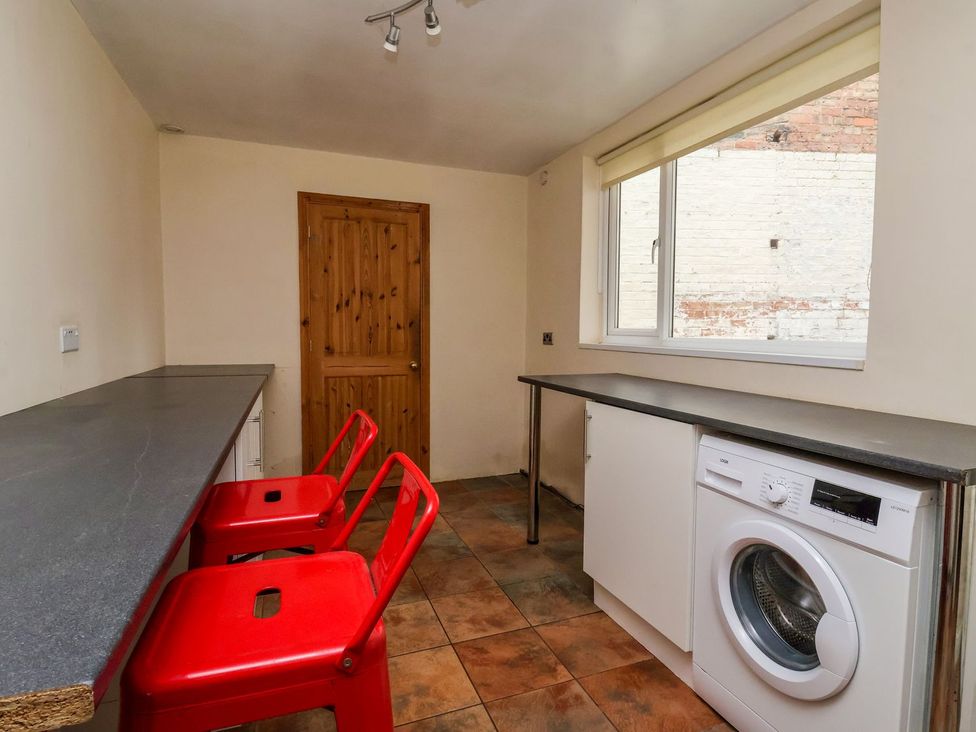 A kitchen with a washing machine and red chairs at Trinity Lodge in Bridlington