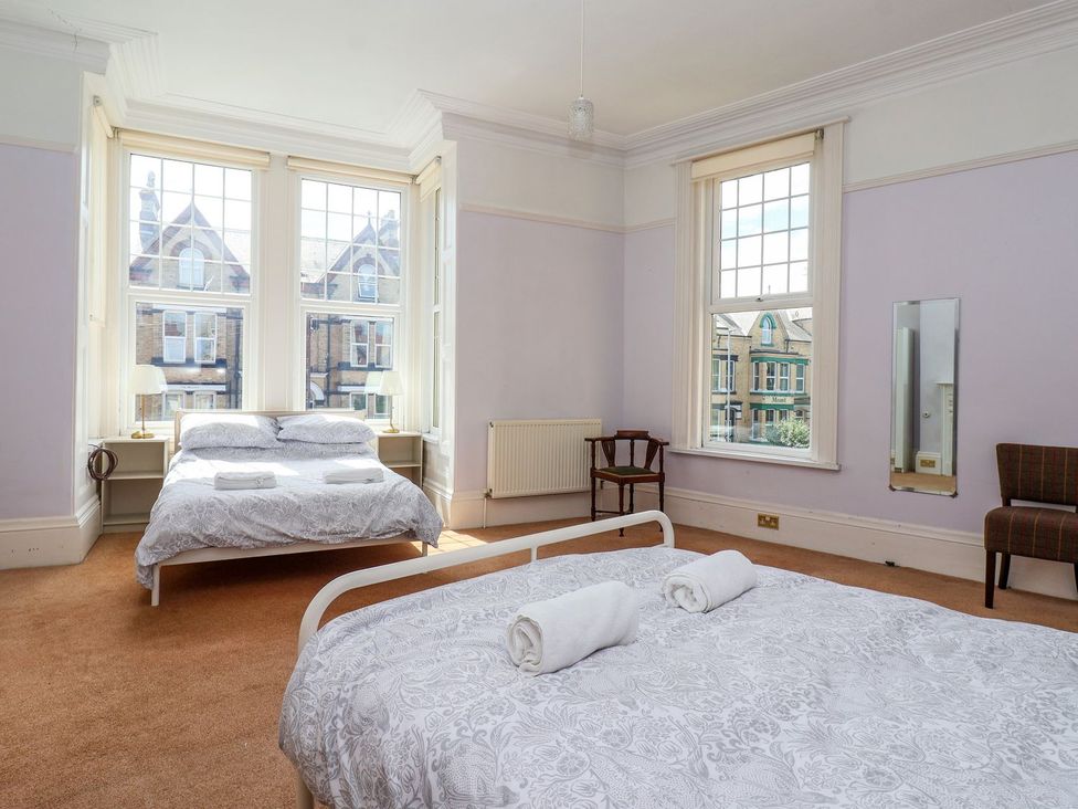 A bedroom with two beds and a chair at Trinity Lodge in Bridlington