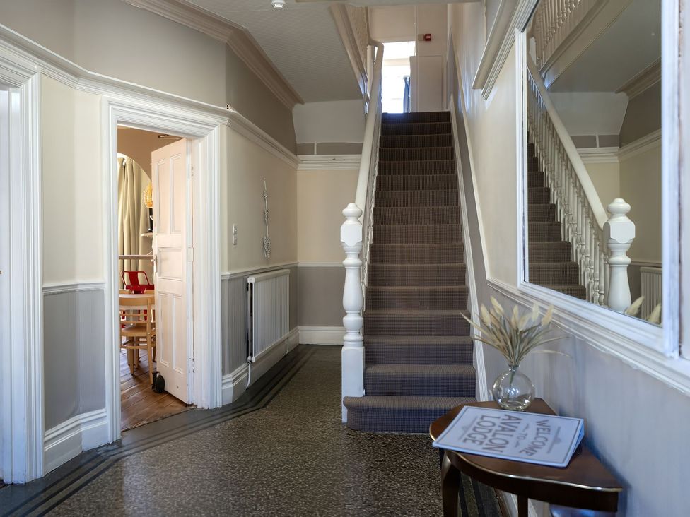 A hallway with staircase and mirror at Avalon Lodge Bridlington