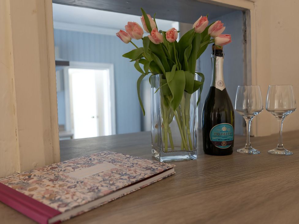 A table with a vase of tulips and a bottle of prosecco at Avalon Lodge Bridlington