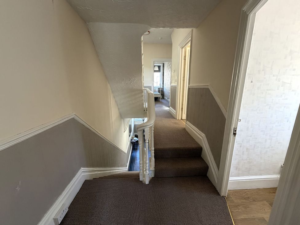 A hallway with staircase and doors at Avalon Lodge in Bridlington