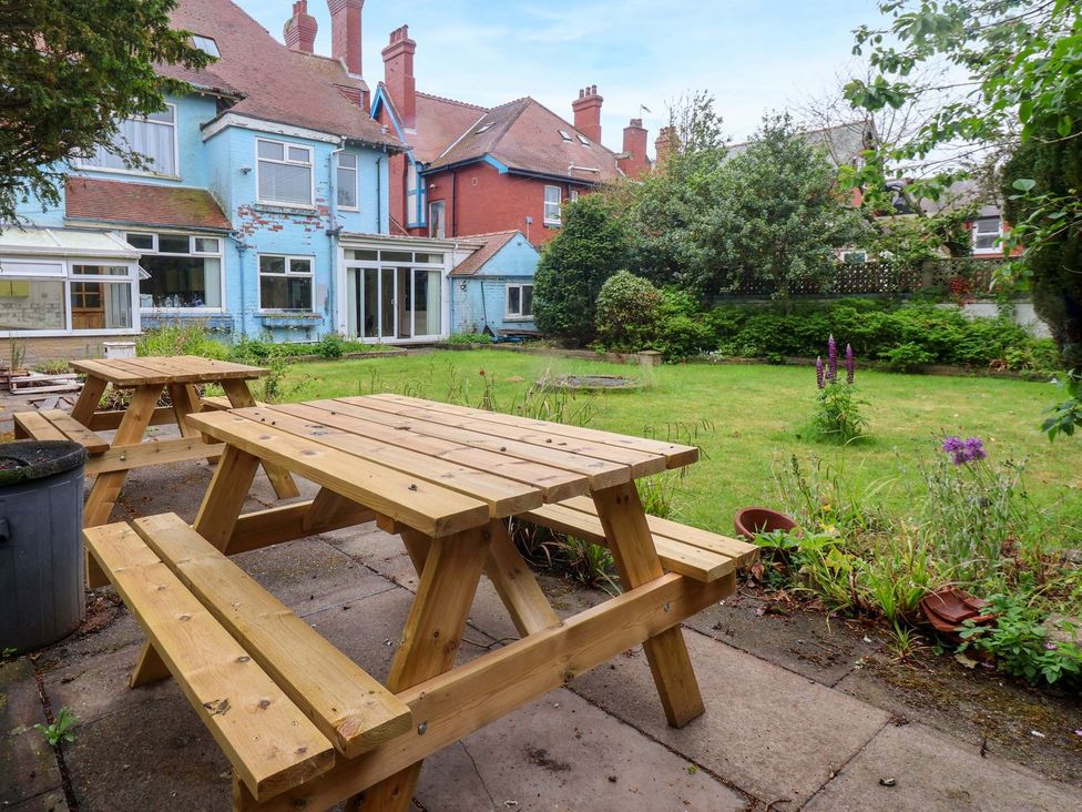 A garden with a wooden picnic table and grass at Sunrise Lodge in Bridlington