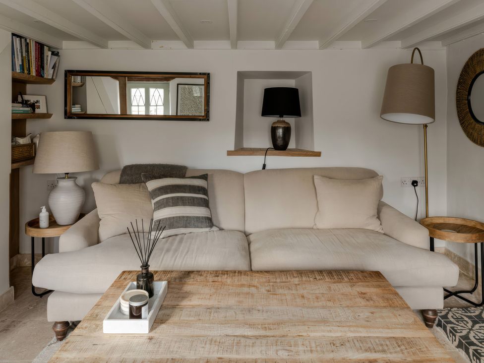 A living room with a sofa, coffee table, and shelves at Rose Cottage in Gweek