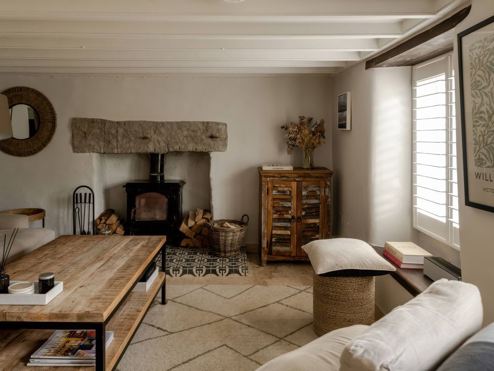 A living room with a fireplace and wooden table at Rose Cottage in Gweek