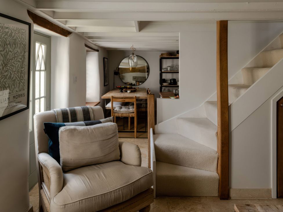 A living room with an armchair and dining table at Rose Cottage in Gweek