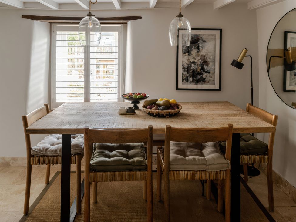A dining room with a wooden table and fruit bowl at Rose Cottage in Gweek