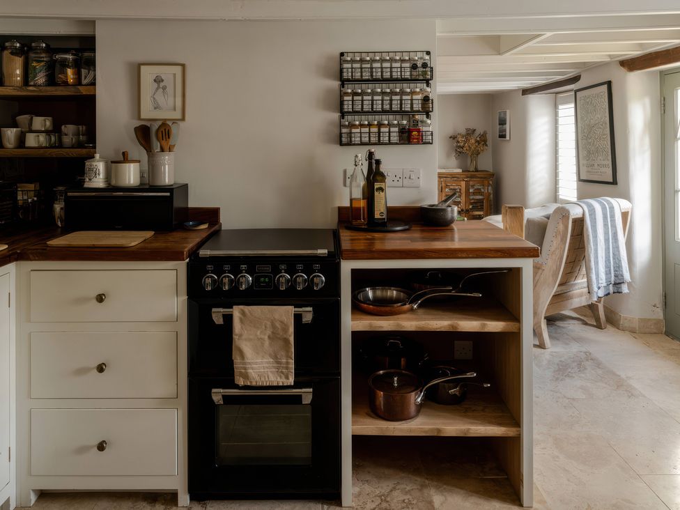 A kitchen with a cooking range and storage shelves at Rose Cottage in Gweek