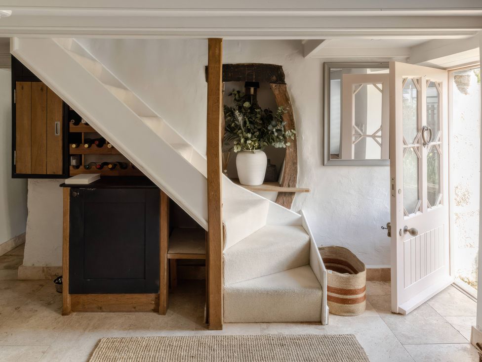 A hallway with stairs and a wine rack at Rose Cottage in Gweek