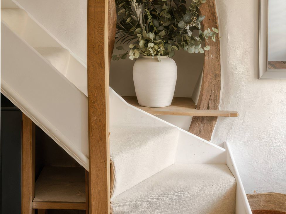 A staircase with decorative foliage in a vase at Rose Cottage Gweek