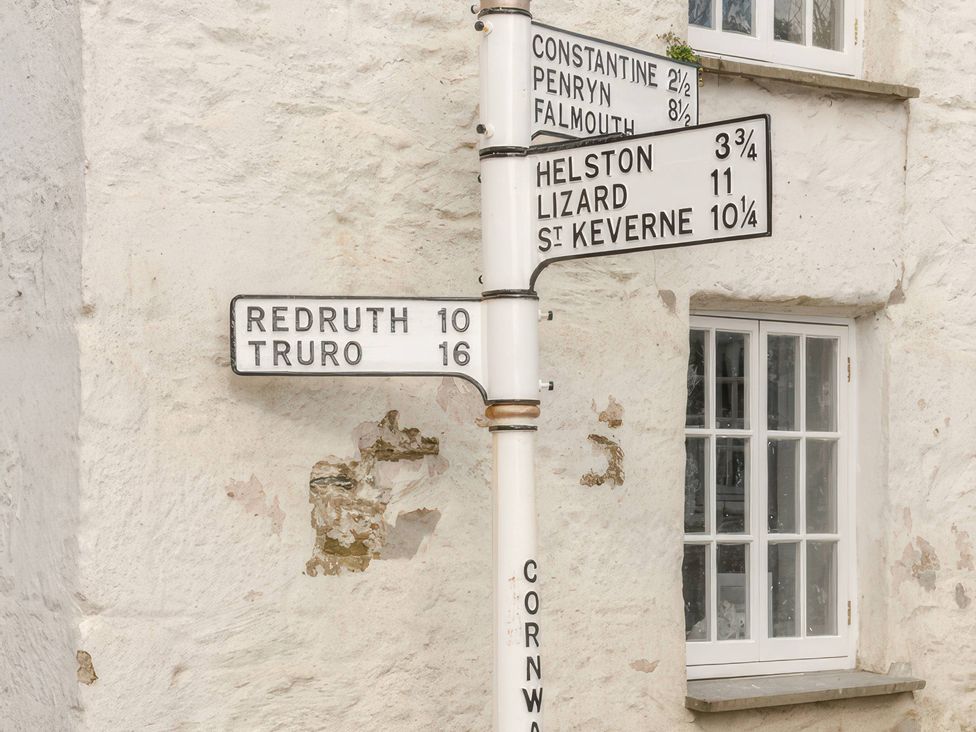 A directional signpost with distances to various locations at Rose Cottage in Gweek